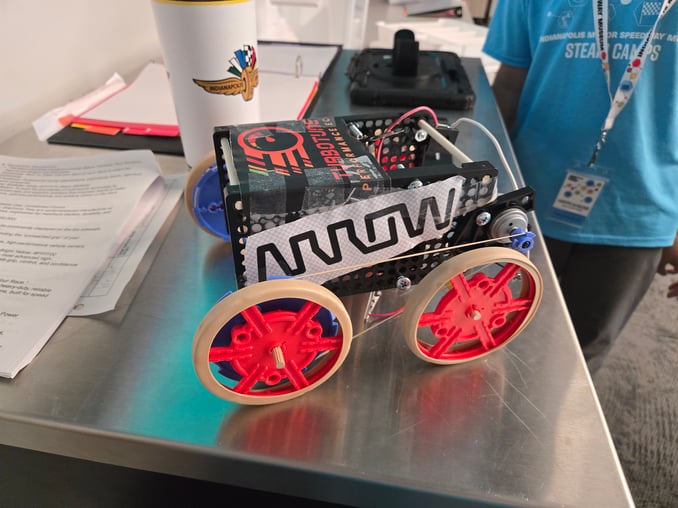 A small car created and programmed created by a student at the summer camp sits on a silver worktabl…