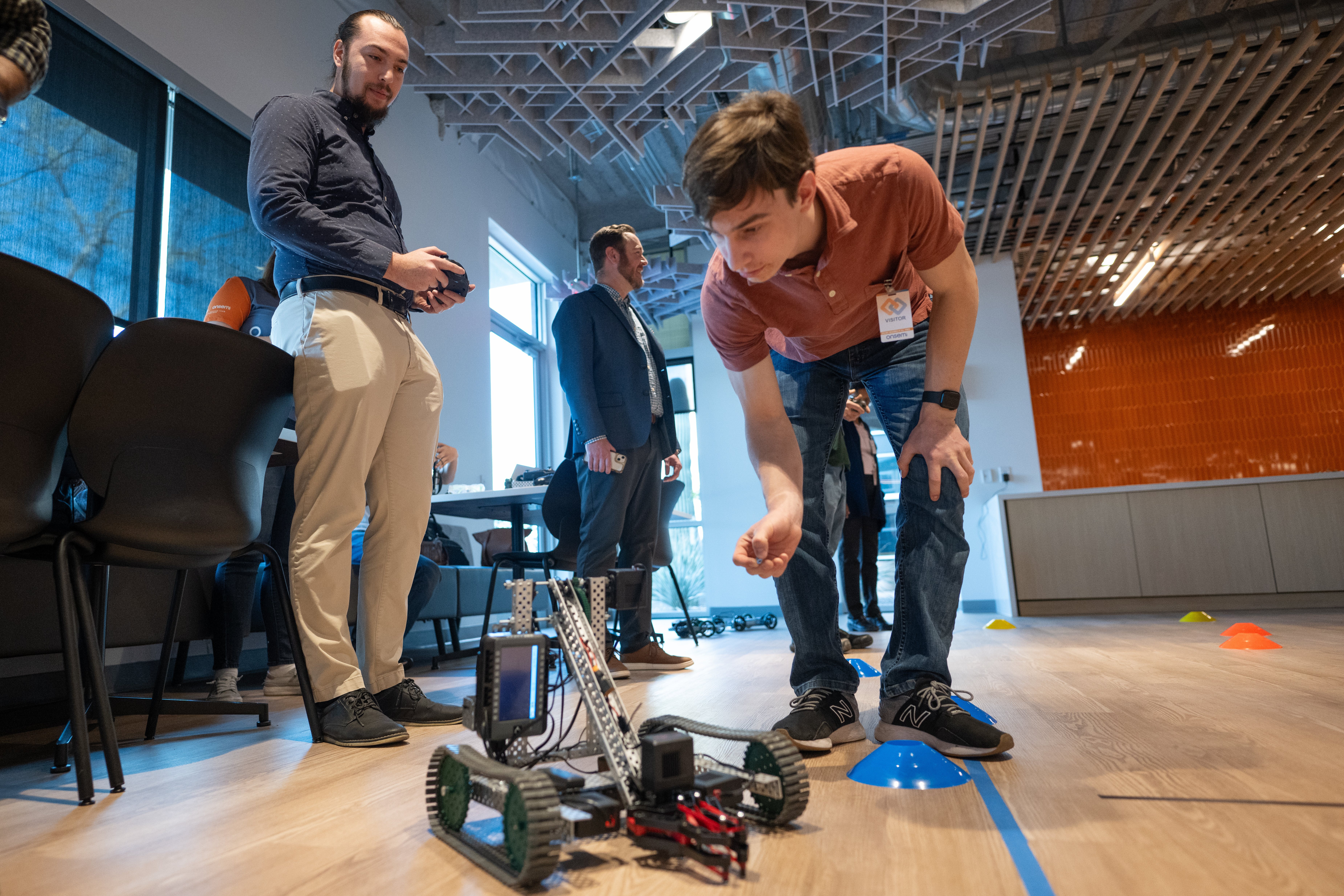 Nathaniel Beeler from onsemi races an RC car as the student who designed it stands by, offering tech…
