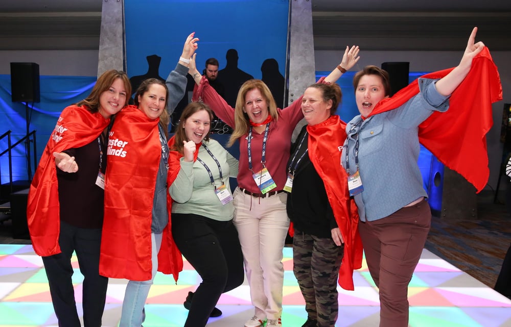Female teachers in red superhero capes at PLTW MasterMinds 2025