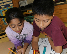 Two pltw students writing on a piece of paper together 