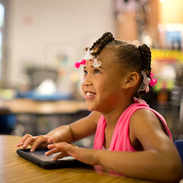 A PLTW Launch student smiling at a desk using equipment 