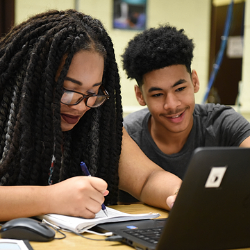 Two computer science students working together on a laptop. 