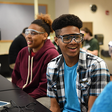 Two engineering students wearing safety glasses and smiling. 