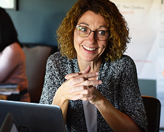 PLTW teacher sitting at desk smiling 